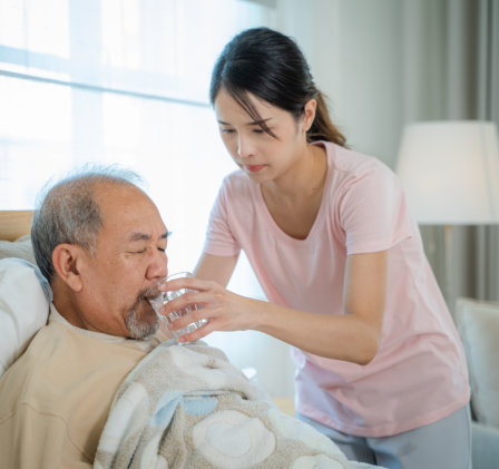 caregiver giving water to elderly