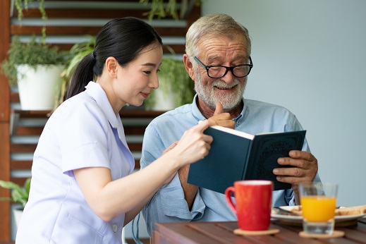 carer and senior man reading a book