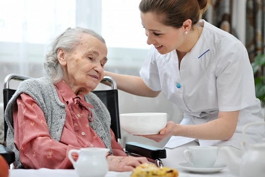 healthcare worker serving food to senior woman
