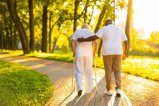 carer and senior man walking outdoors